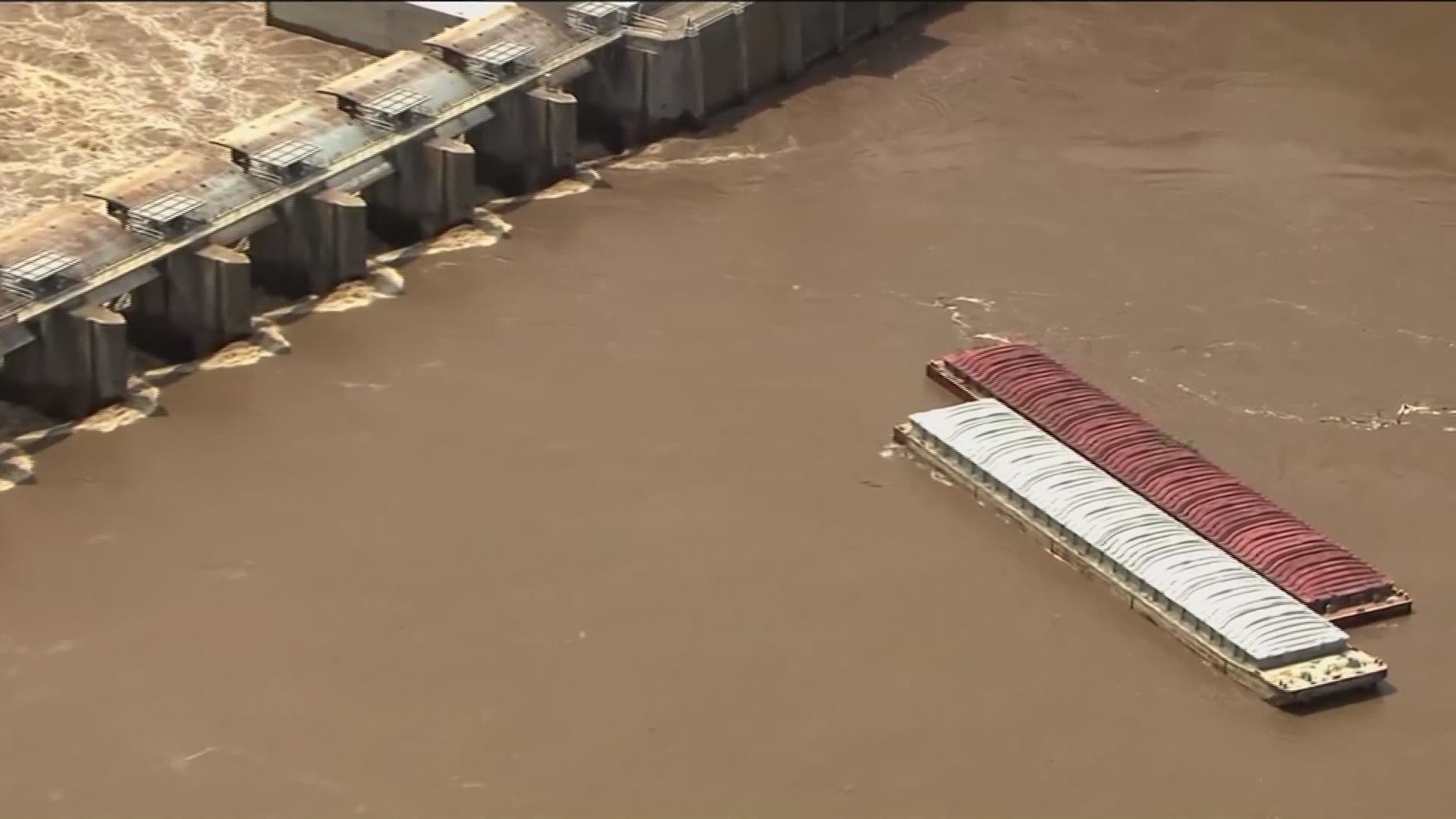 Two barges that broke loose on the swollen Arkansas River have struck a dam in Oklahoma, and at least one sank into the river.