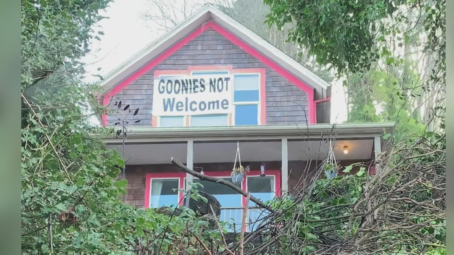 One neighbor's banner reads, "Goonies not welcome." The new owner's banner says they are. And a third neighbor's banner calls the first neighbor "Karen."