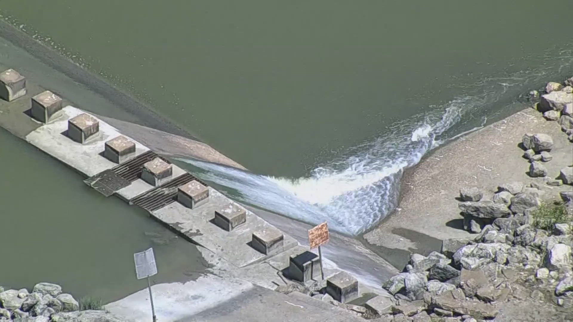 Officials say the man and his father were fishing near the spillway when he was pulled underwater.