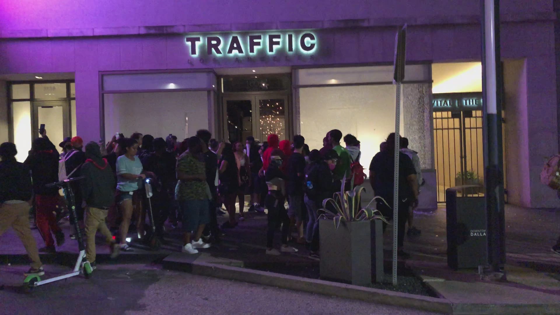 People are seen jumping into the front window of LA Streets in Dallas after smashing it, then leaving with piles of new clothing.