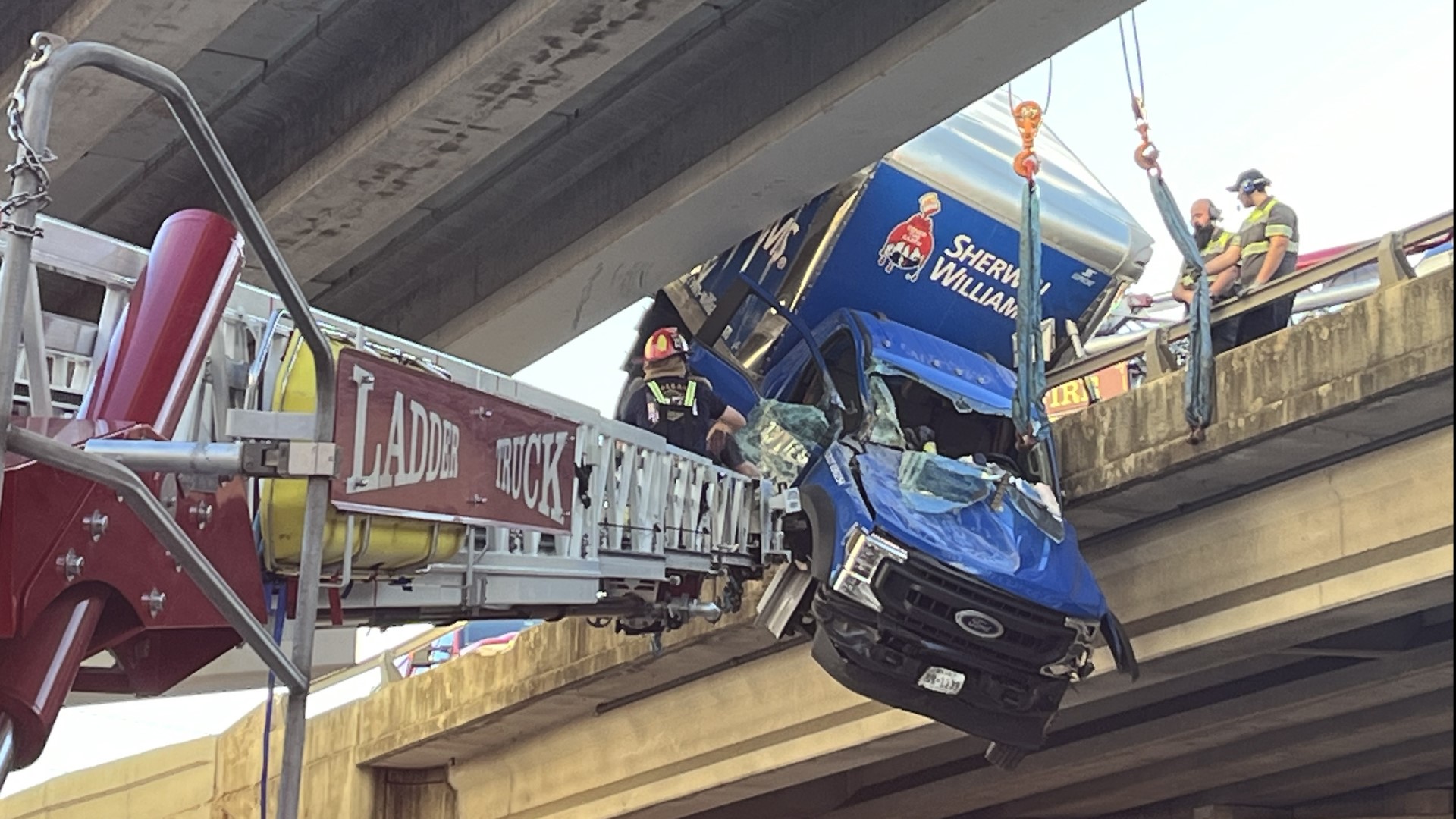 The box truck was hanging off of the Stemmons Freeway overpass with the driver still stuck inside on Monday afternoon.