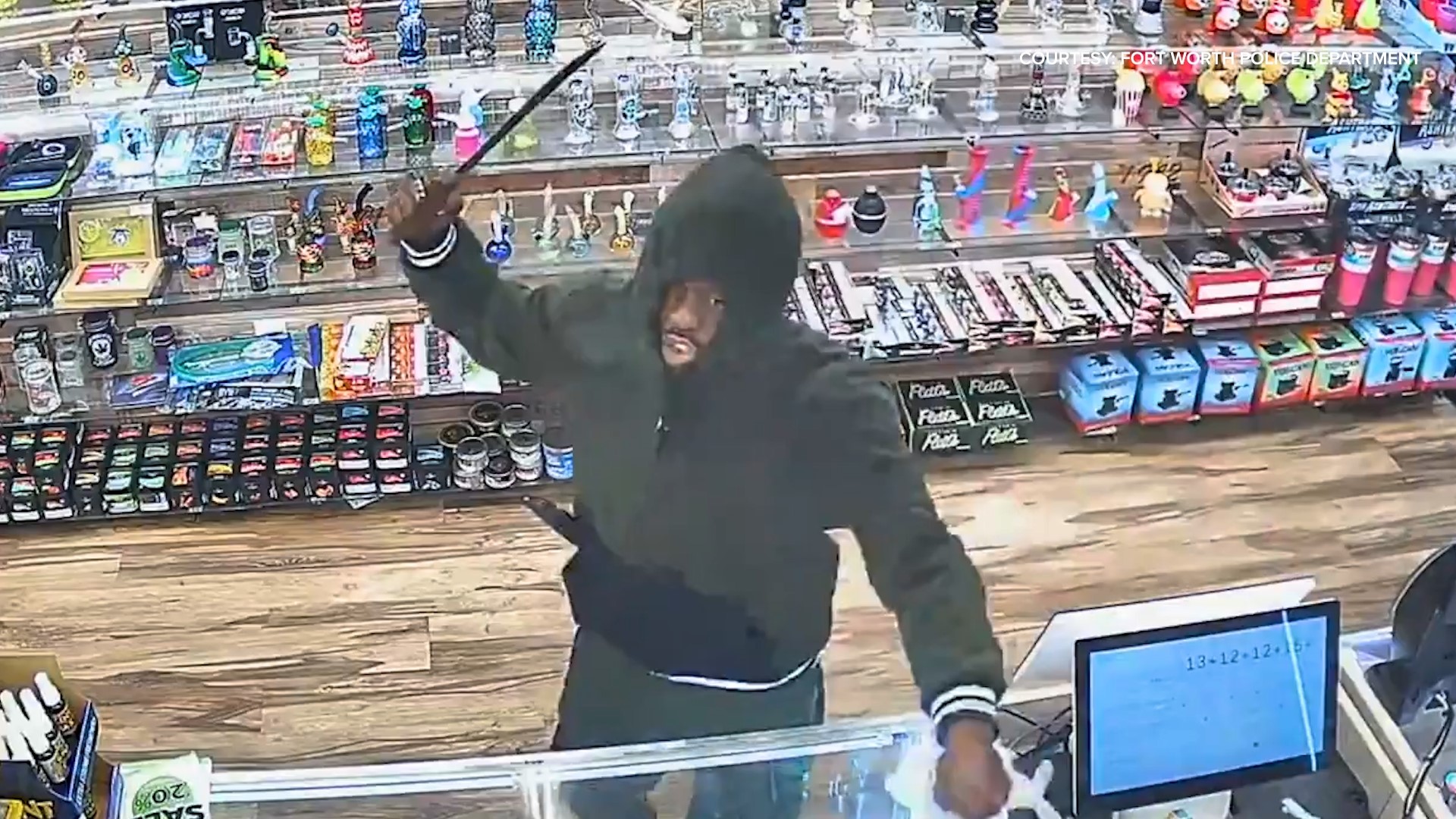 Surveillance video shows a suspect in a black hoodie and black sweatpants going into a store and using a machete during the robbery.